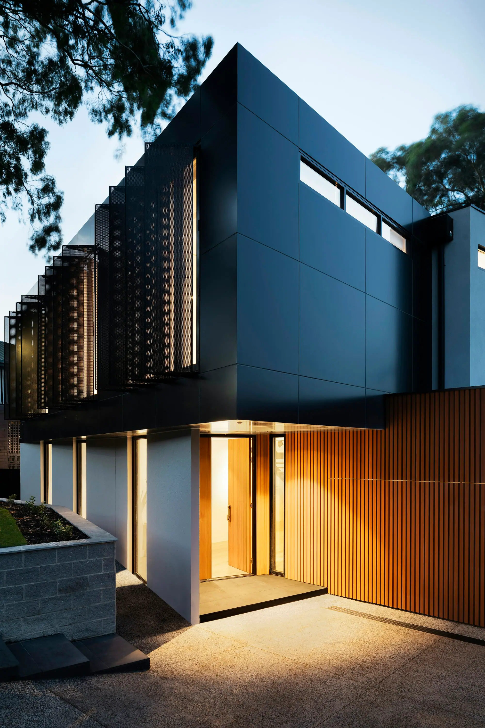 Contemporary building facade with timber screens lit at dusk